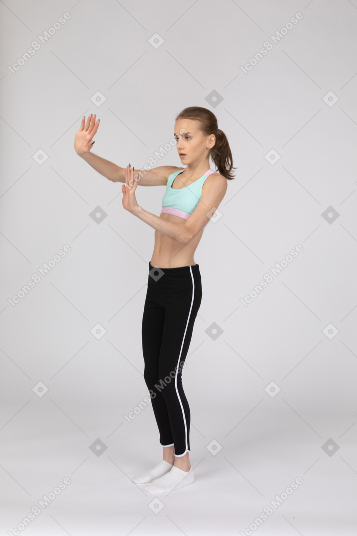 Three-quarter view of a teen girl in sportswear outstretching hands