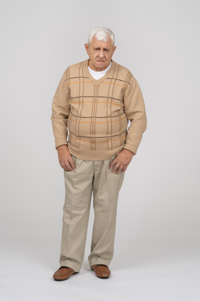 Front view of a grumpy old man in casual clothes looking at camera