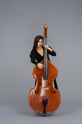 Front view of a young woman in black dress playing her double-bass