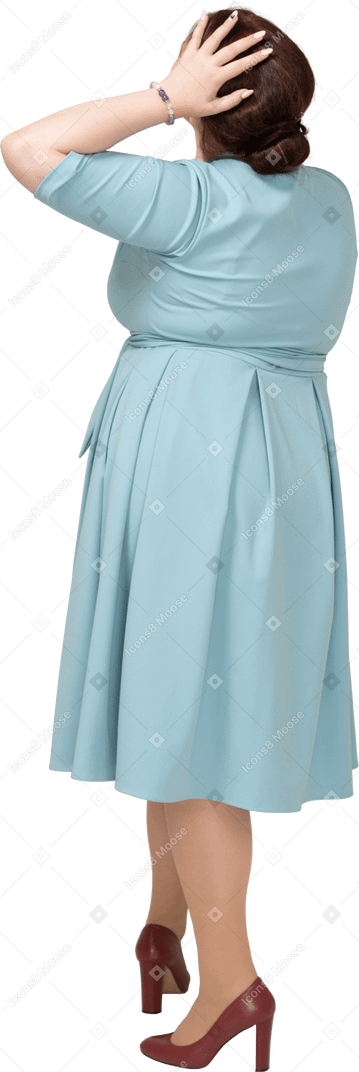 一个身着蓝色连衣裙、手放在头上的女人的后视图
