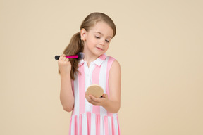 Cute little girl applying makeup