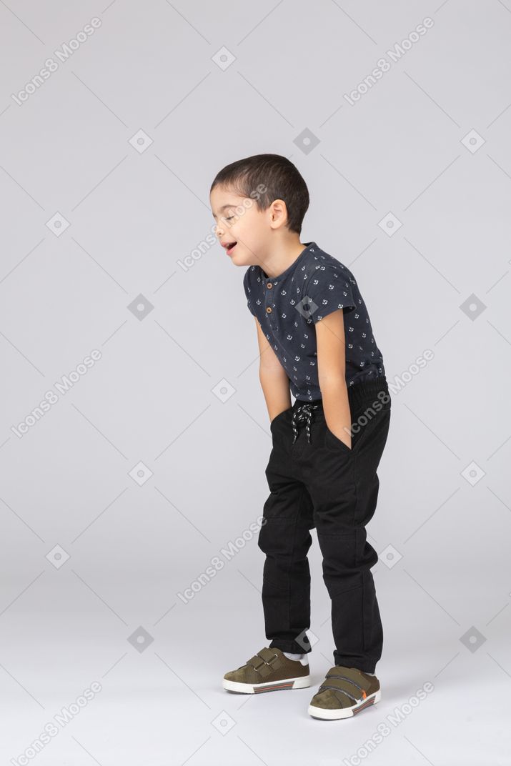 Vista lateral de um menino bonito posando com as mãos nos bolsos