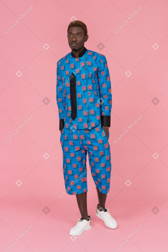 ピンクの背景に立っている青いパジャマで黒人男性