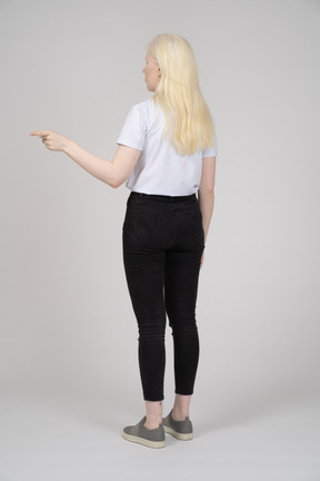 Rear view of a young girl standing and pointing to the side