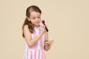 Cute little girl applying makeup