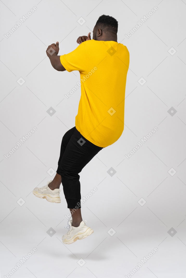 노란 티셔츠를 입은 검은 피부의 젊은 남자가 뒤로 점프하는 모습