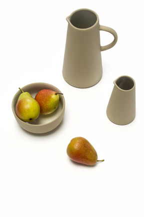 Pears in a bowl next to two jugs