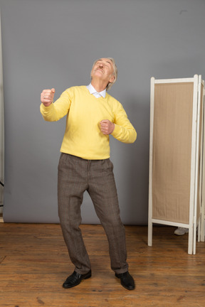 Front view of a dancing old man clenching fists while leaning back