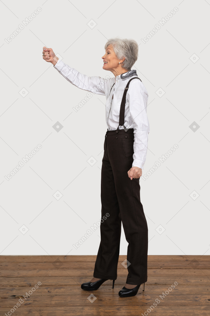 Side view of a smiling old lady raising her hand
