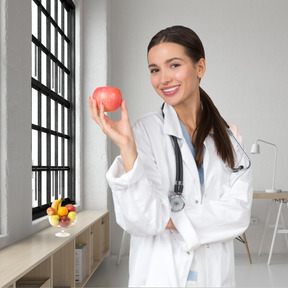 A smiling doctor holding an apple