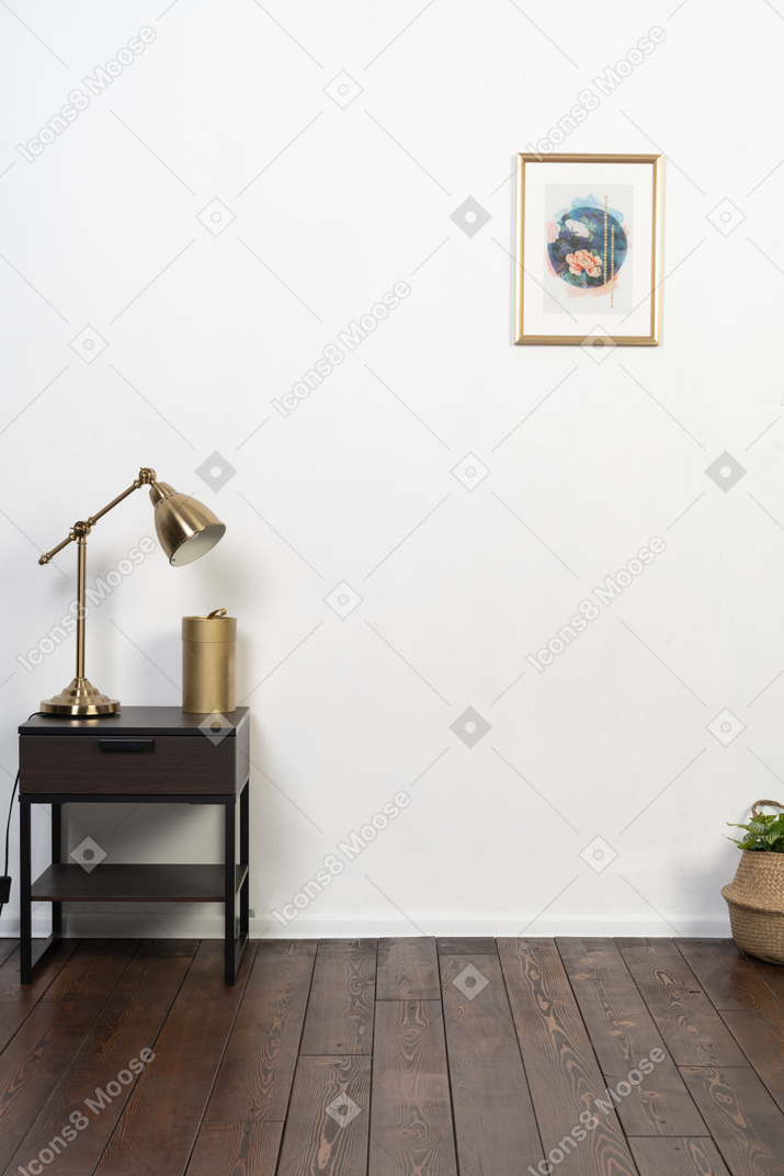 흰색 벽, 나무 바닥 및 나이트 스탠드에 황동 램프가있는 멋지고 단순한 방