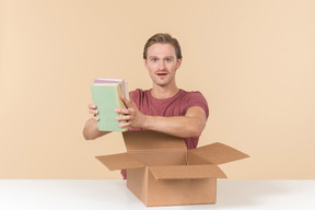 Excited young guy looking at books he's got from the box