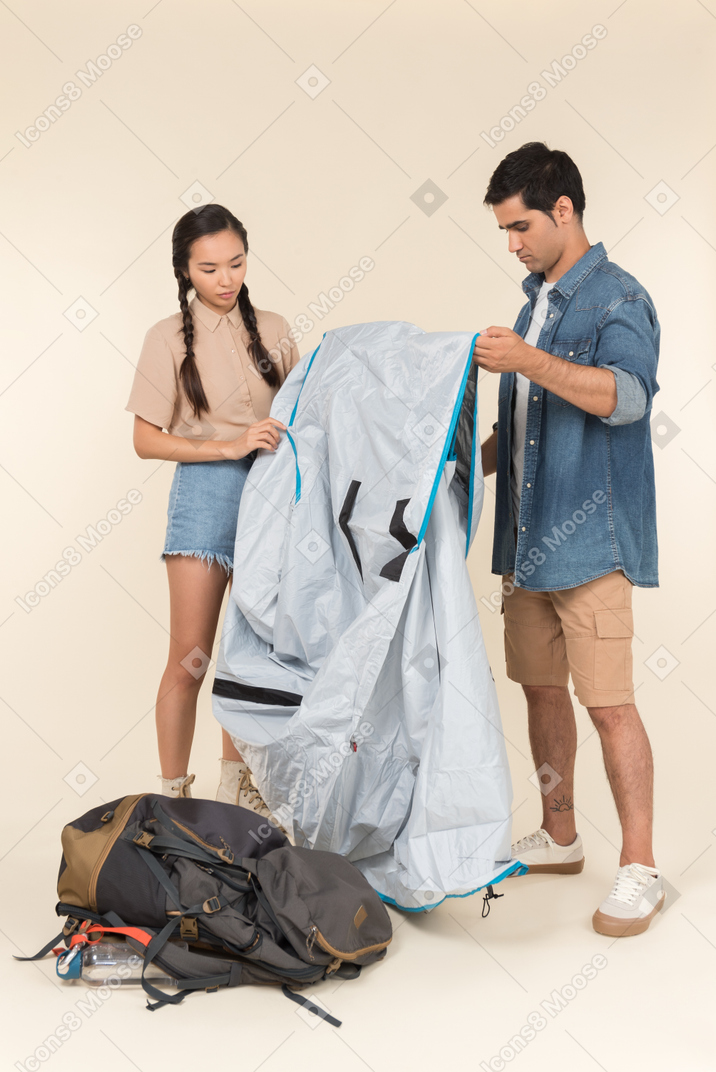 Young interracial couple setting up a tent