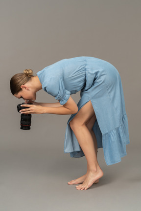 Side view of a young woman in blue dress taking shot