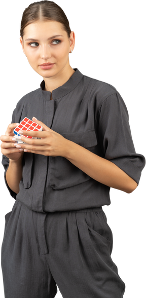 Three-quarter view of young woman in a jumpsuit holding the rubik's cube