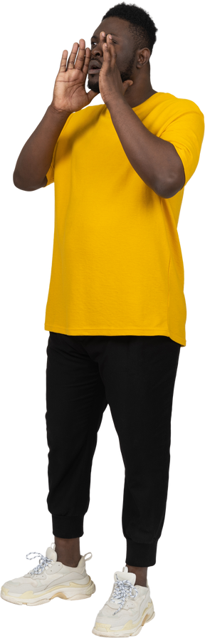 Vue de trois quarts d'un jeune homme à la peau foncée hurlant en t-shirt jaune