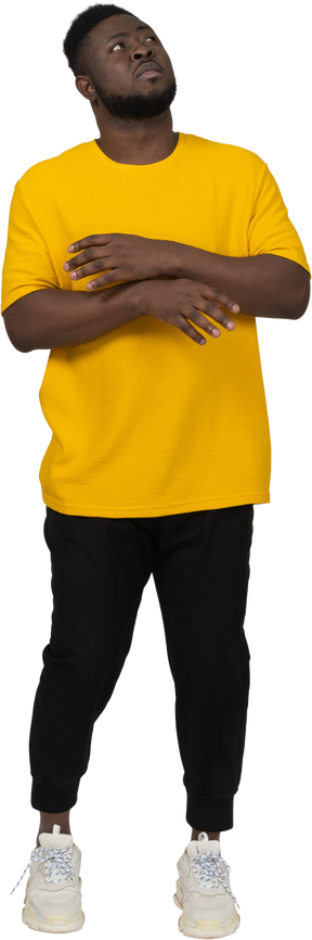 Vista frontal de un joven de piel oscura con camiseta amarilla levantando las manos