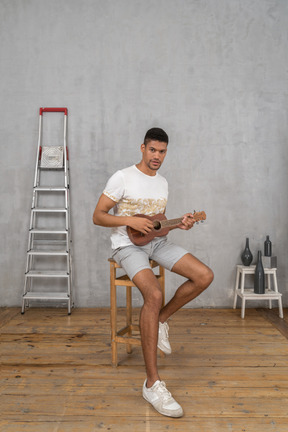 Vista di tre quarti di un uomo in posa con l'ukulele