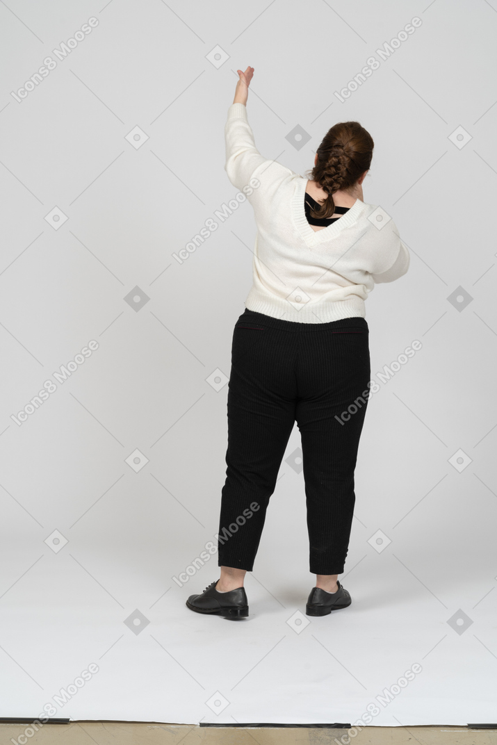 Rear view of a plump woman in casual clothes with raised arm