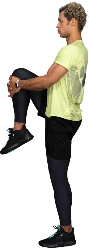 Side view of a dark-skinned young man pressing knee to chest