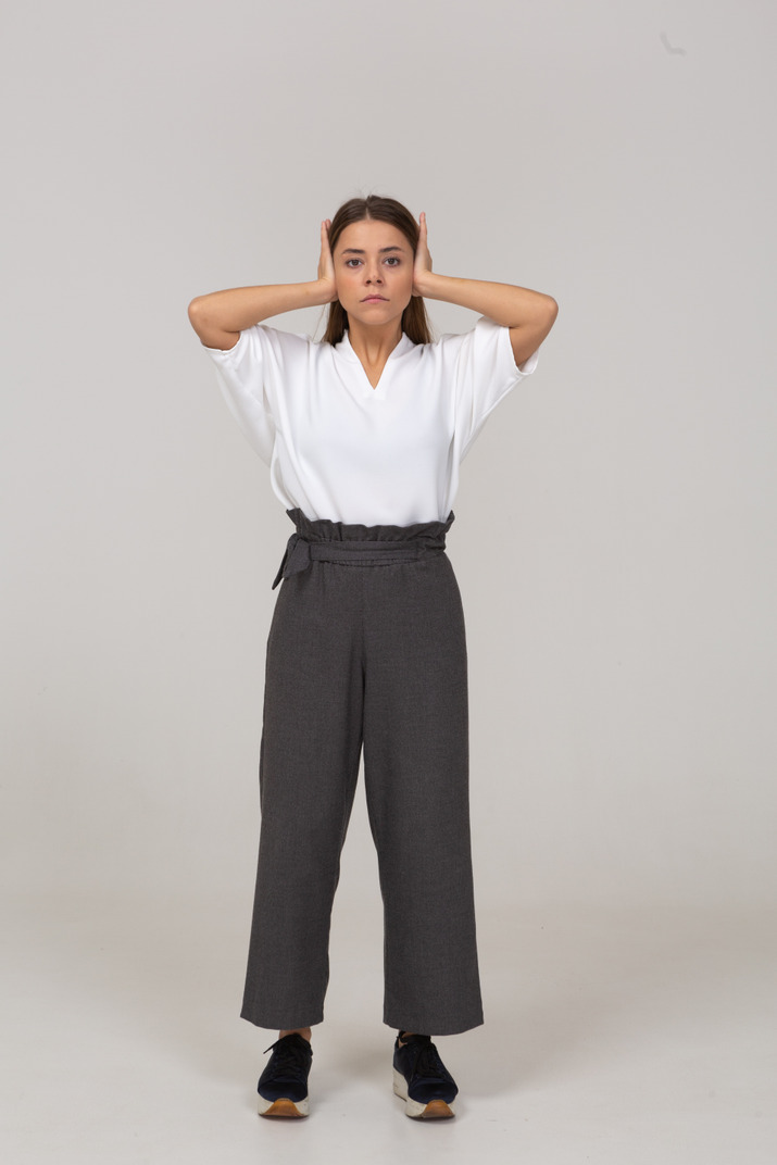 Front view of a young lady in office clothing touching her ears
