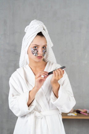 Woman in bathrobe filing her nails