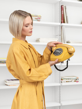 A woman in a yellow coat is holding a yellow phone