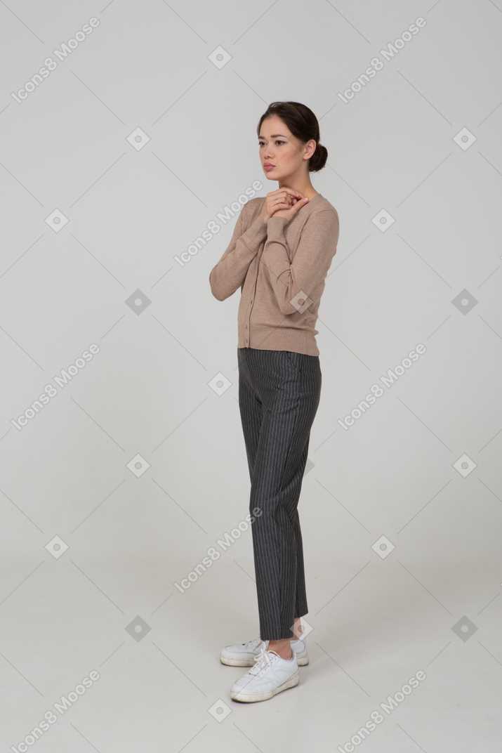 Three-quarter view of a worried young lady in beige pullover holding hands together