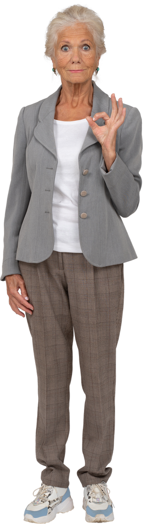 Vista frontal de una anciana en traje mostrando signo ok