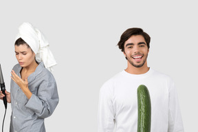 A woman with a hair curler and a man with a cucumber in front of him