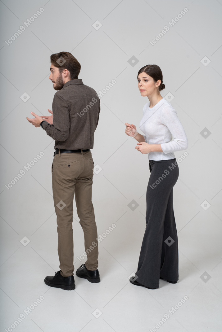 Three-quarter back view of a curious young couple in office clothing