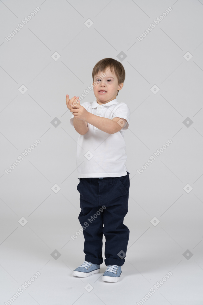 Front view of a little boy holding his own hand