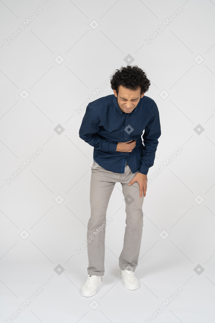 Vista frontal de um homem com roupas casuais sofrendo de dor de estômago