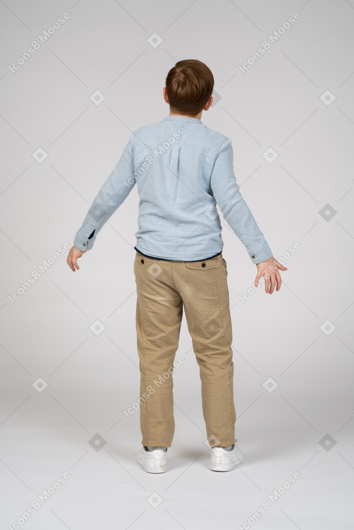 Back view of a boy standing with his arms outstretched