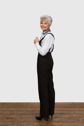 Full-length if an old female in office clothes turning back and smiling