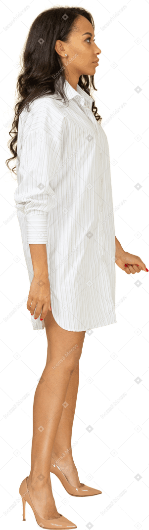 Vue latérale d'une jeune femme à la peau sombre en robe blanche serrant le poing