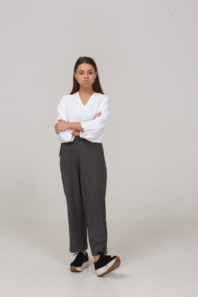 Vista frontal de uma jovem com roupa de escritório soprando bochechas e cruzando os braços