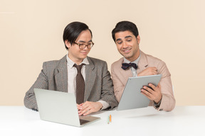 Dois jovens nerds sentado à mesa e usando gadgets