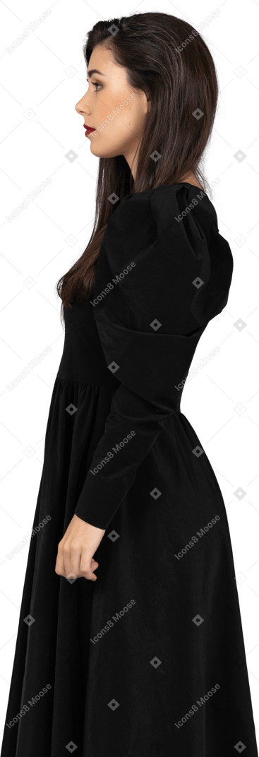 一位年轻的女士，穿着黑裙子站着不动的侧视图