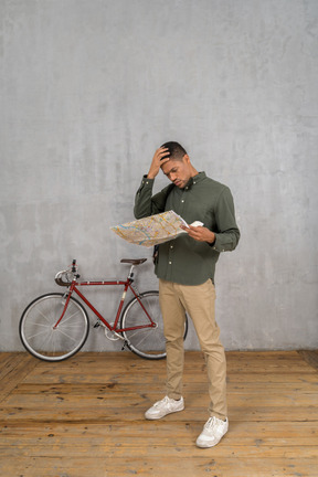Three-quarter view of a man examining a map looking troubled