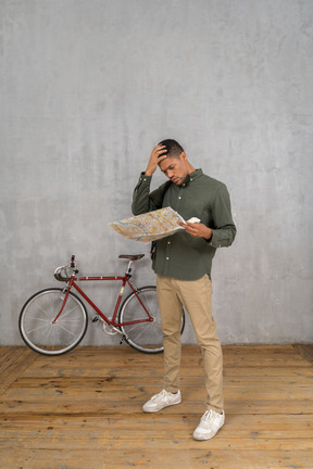 Vue de trois quarts d'un homme examinant une carte à l'air troublé