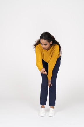 Front view of a girl in casual clothes bending down and making warning sign