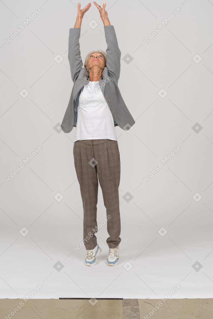 Vue de face d'une vieille dame en costume debout sur les orteils et levant les bras