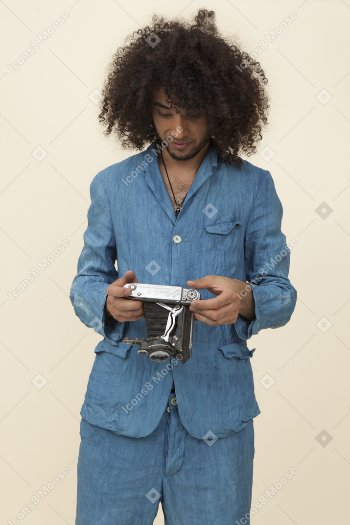 Africana con grandi capelli ricci che regge una macchina fotografica d'epoca