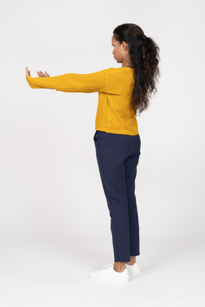 Side view of a girl in casual clothes standing with extended arms