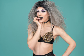 Drag queen in studded bra biting finger