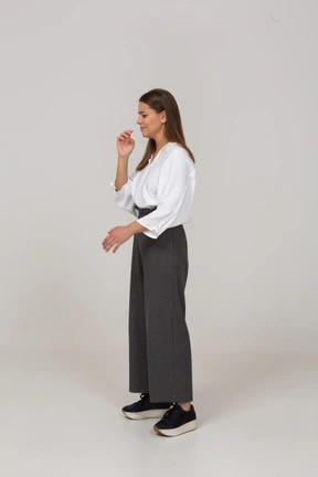 Three-quarter view of a displeased young lady in office clothing waving hand