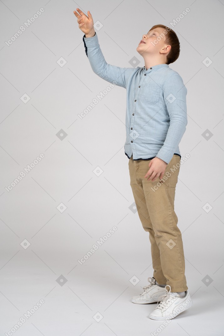 Side view of a boy pointing up with hand