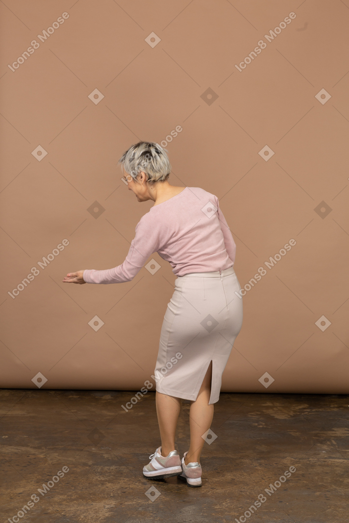 Vista traseira de uma mulher com roupas casuais fazendo um gesto de boas-vindas