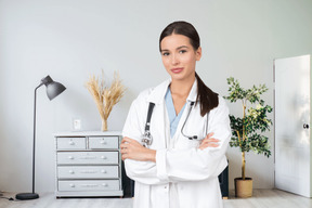 A woman in a white lab coat standing with her arms crossed
